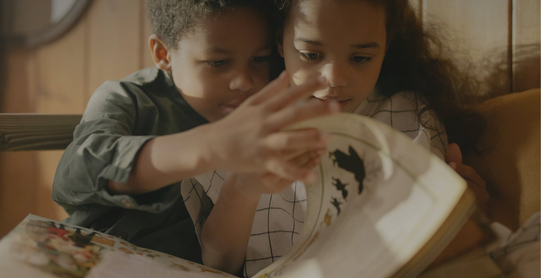 Two children reading a book.